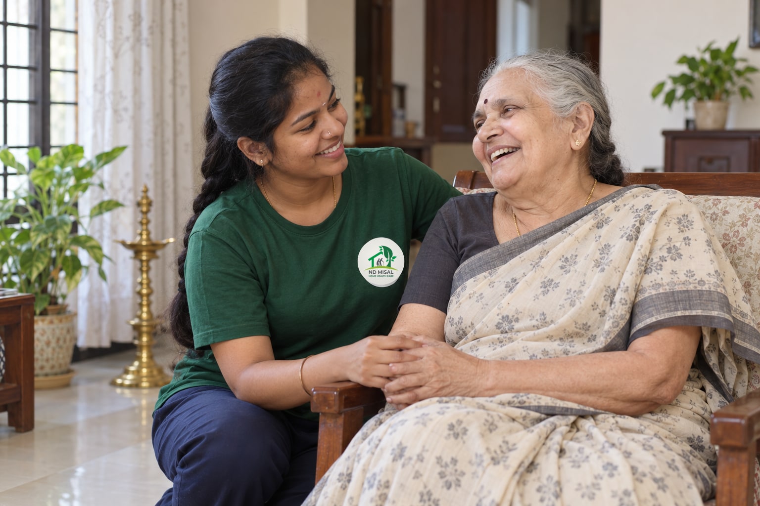 ND Misal caregiver holding hands and laughing with an elderly woman at her home in Bangalore